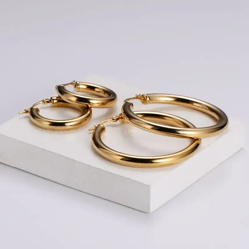 Classic Hoops – Waterproof gouden oorbellen op witte achtergrond – Meena Rotterdam